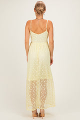 woman wearing a light yellow lace maxi dress with a fitted bodice and a flowing skirt, shown from the back