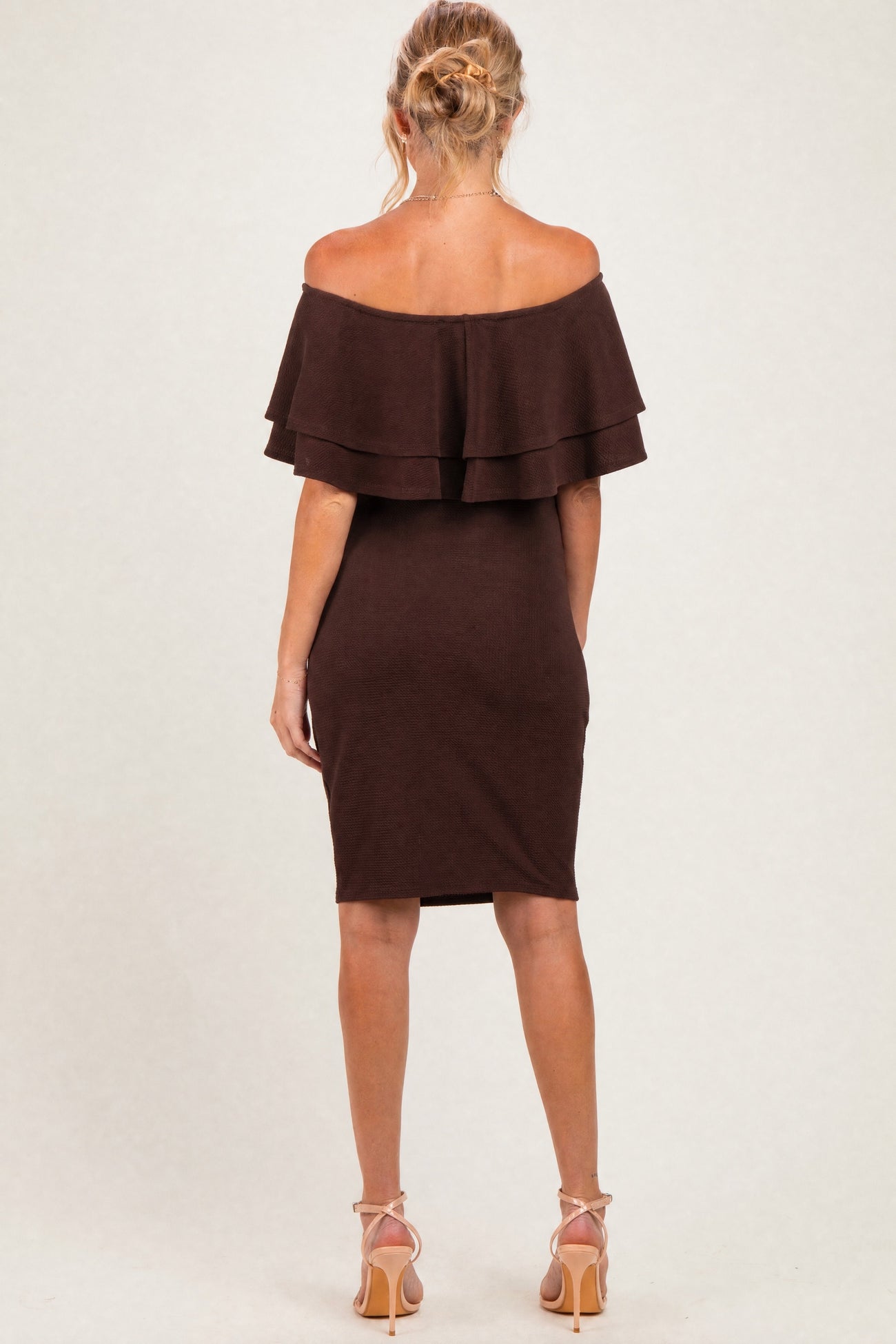 woman wearing a brown off-the-shoulder maternity dress with layered ruffles and a fitted silhouette