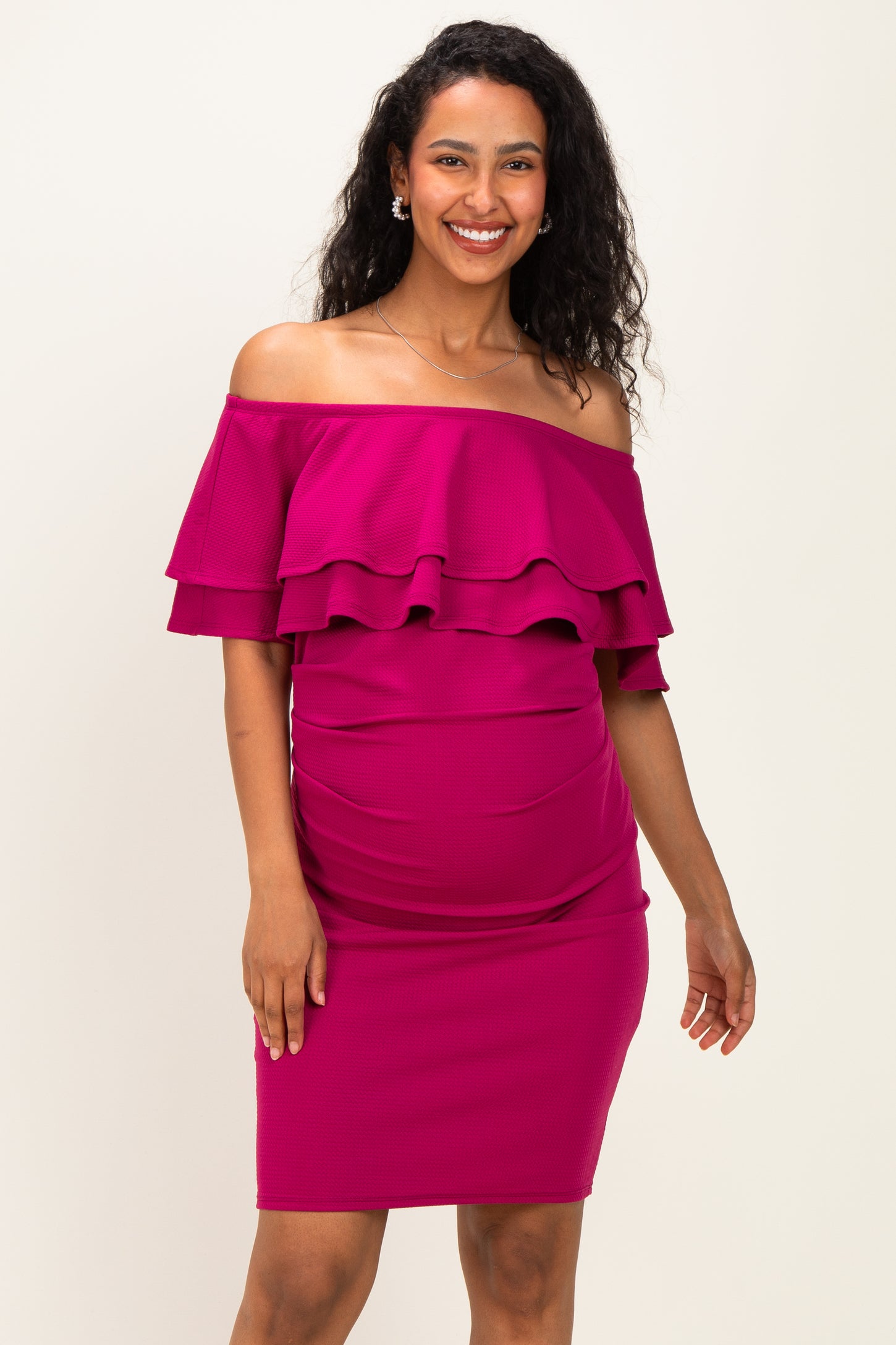 woman wearing a magenta off-the-shoulder maternity dress with ruffled layers and a fitted silhouette, showing baby bump