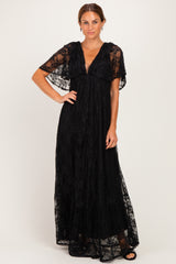 woman wearing a black lace maxi dress with flutter sleeves and a deep v-neckline