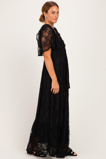 woman wearing a black lace maxi dress with short flutter sleeves and tiered skirt details
