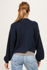 woman wearing a navy blue maternity sweater with a loose fit and balloon sleeves, seen from the back