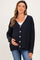 woman wearing a dark navy maternity cardigan with buttons, holding her baby bump, paired with a white top and jeans