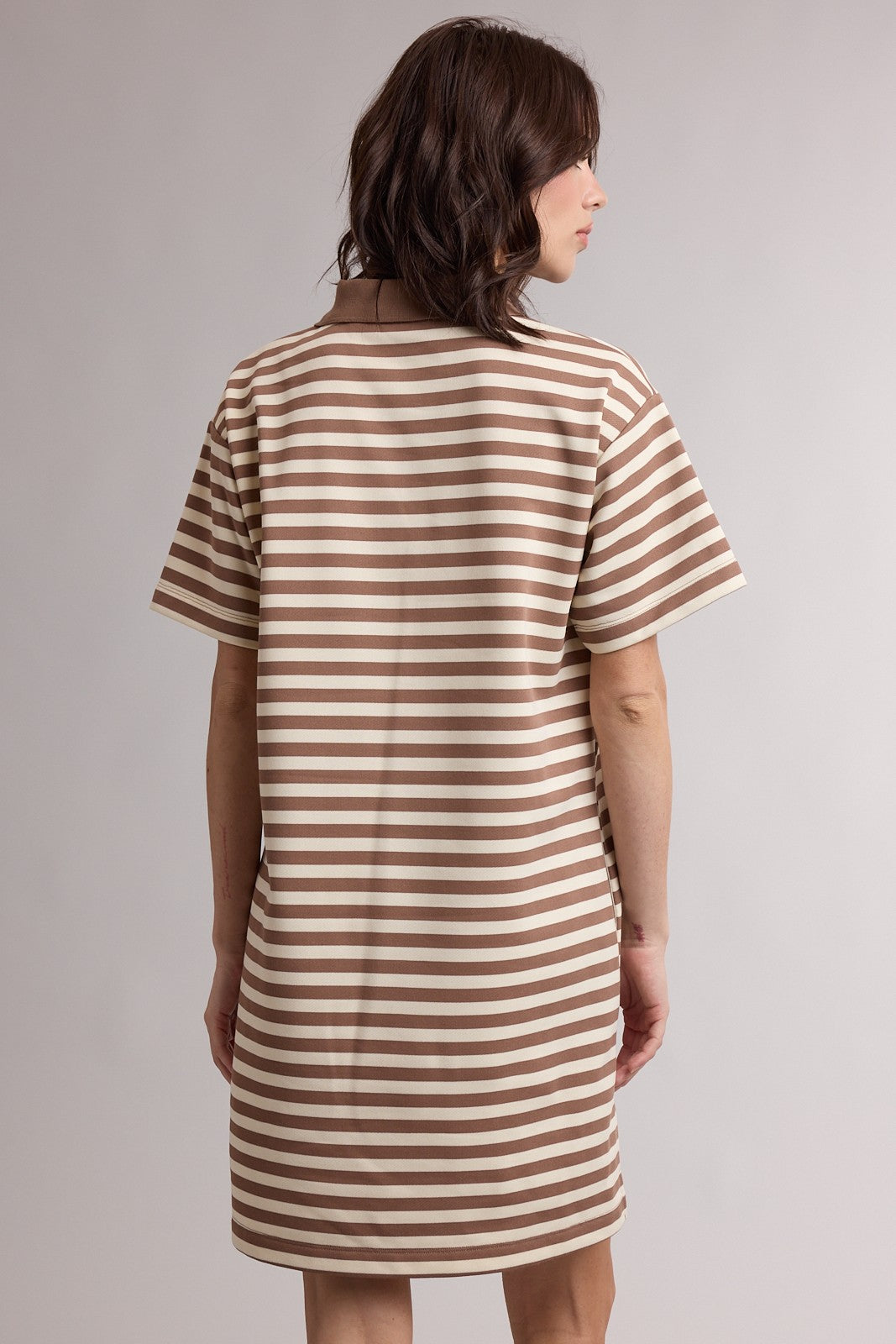 woman wearing a brown and white striped short sleeve dress viewed from the back