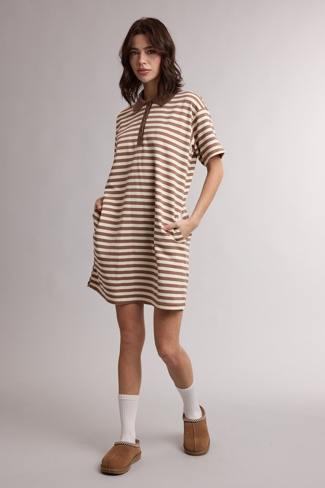 woman wearing a beige and brown striped short sleeve dress with pockets and brown slippers