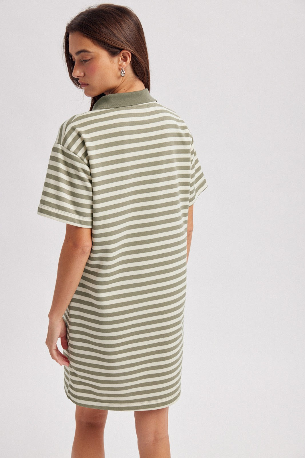 woman wearing a striped olive green oversized polo dress, showing the back view