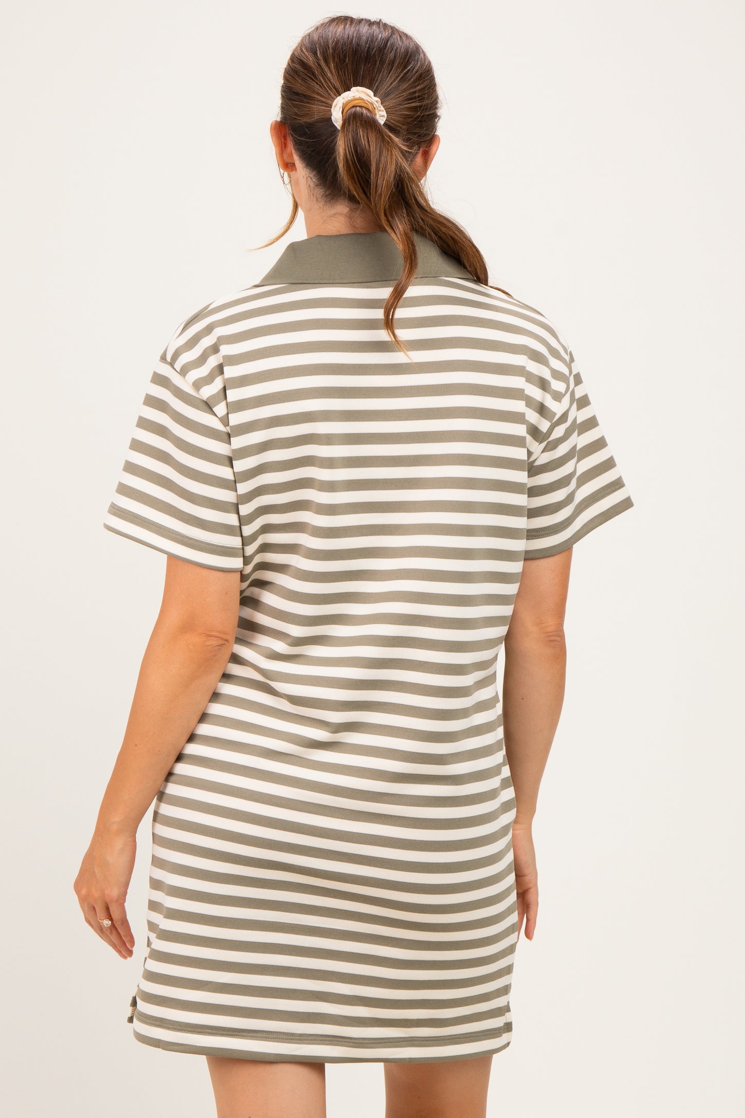 woman wearing a striped maternity polo dress in green and white, shown from the back