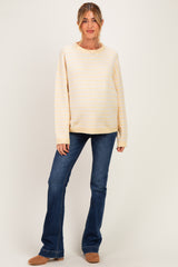 woman wearing a striped yellow maternity sweater with relaxed fit and blue flared jeans