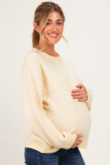 woman wearing a yellow and white striped maternity sweater and holding her baby bump