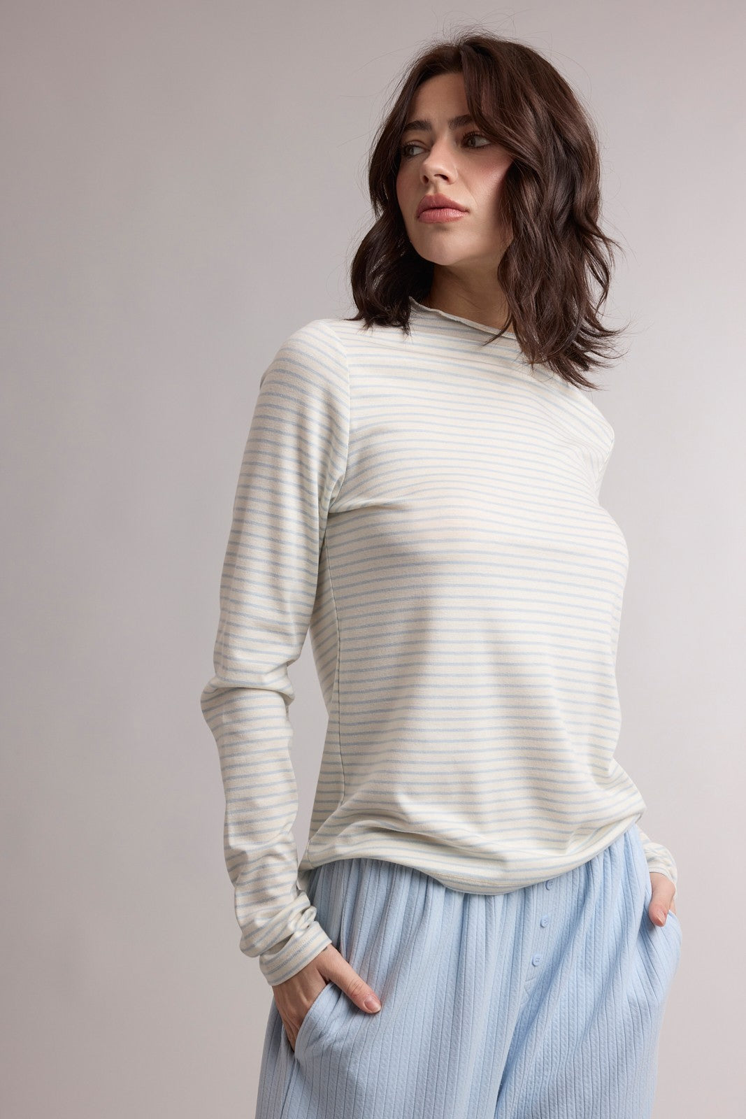 woman wearing a light gray striped long sleeve top with a relaxed fit and light blue pajama pants