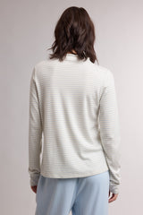 woman wearing a light cream long sleeve shirt with subtle stripes, viewed from the back