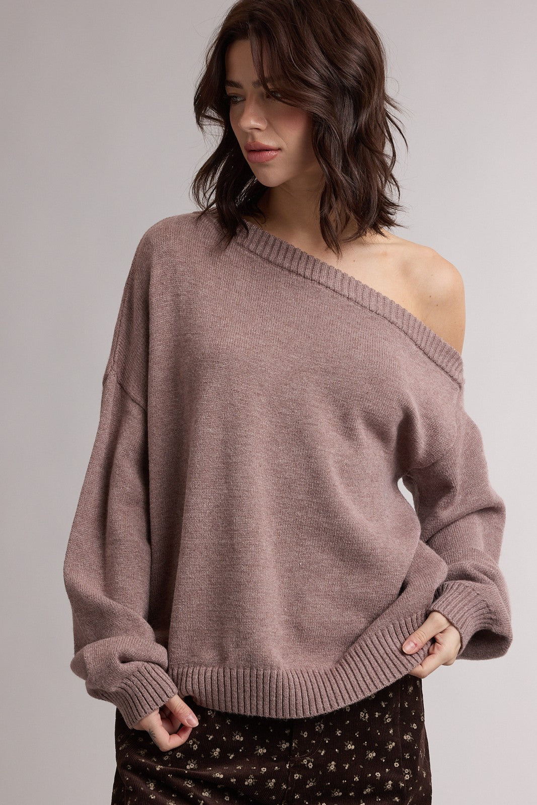 woman wearing a blush oversized off-the-shoulder sweater with wide sleeves and ribbed hem