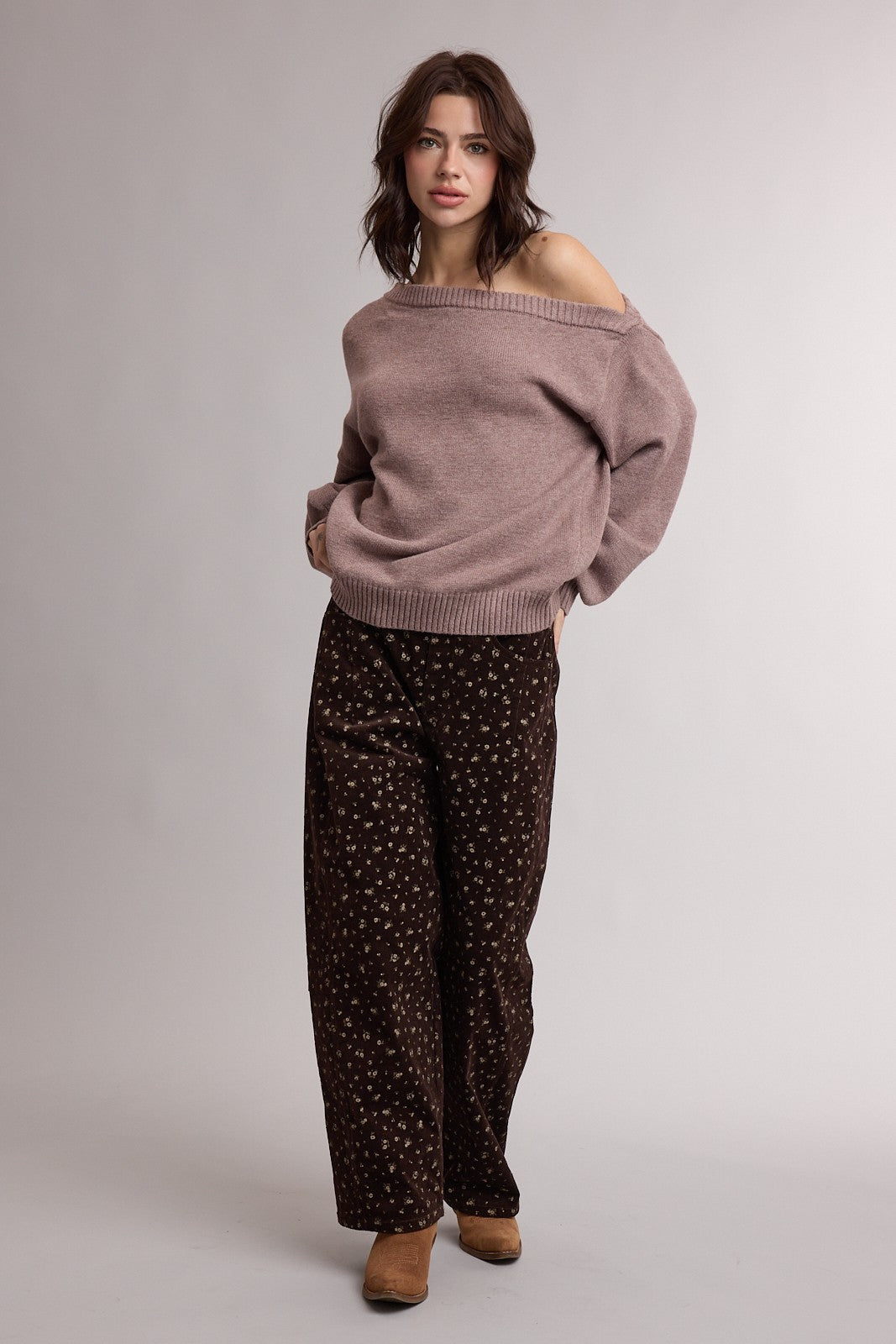 woman wearing a light pink oversized sweater and dark brown wide-leg pants with a floral pattern