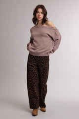woman wearing a light pink oversized sweater and dark brown wide-leg pants with a floral pattern