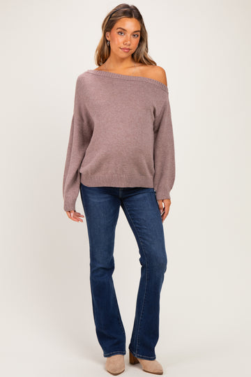 woman wearing a mauve off-the-shoulder maternity sweater with balloon sleeves and blue flared jeans