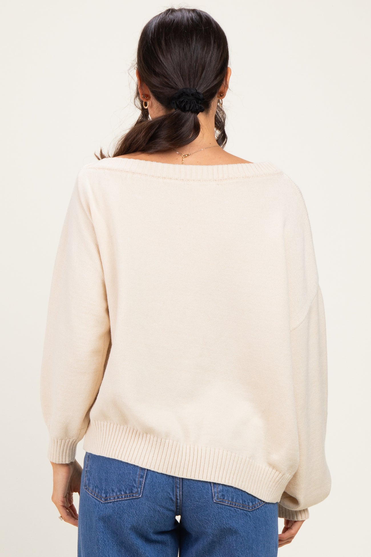 woman wearing a cream oversized sweater with a wide neckline and balloon sleeves, seen from the back