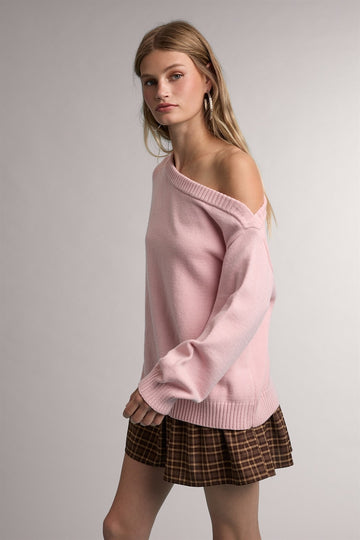 woman wearing a light pink off-the-shoulder sweater paired with a brown plaid mini skirt