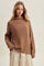 woman wearing a brown knit sweater with a high neckline paired with a floral print skirt