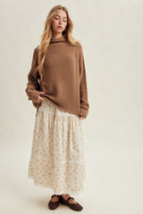 woman wearing a brown oversized sweater with a cream floral maxi skirt and brown flats