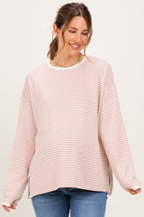 woman wearing a light pink and white striped maternity top with relaxed fit and side slits, smiling at the camera