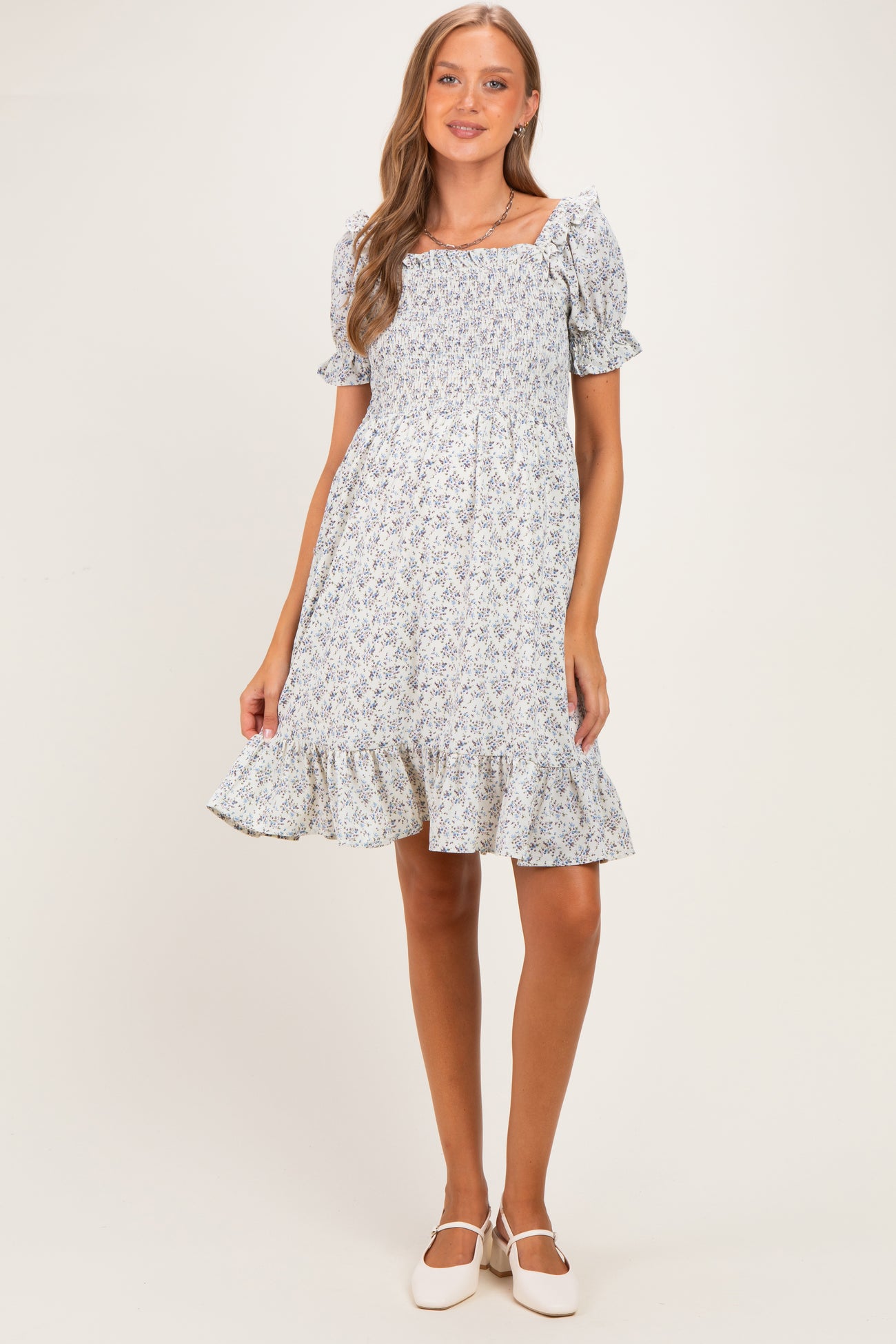 woman wearing a floral print maternity dress with short puff sleeves and a ruffled hem