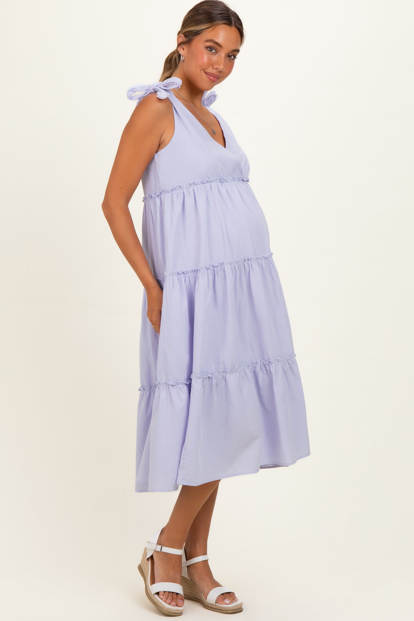 woman wearing a lavender tiered maternity dress with tie straps and a visible baby bump
