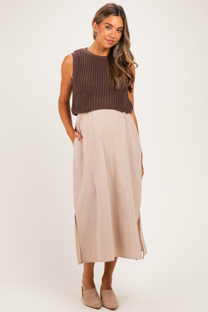 woman wearing a brown knitted maternity top over a beige maxi dress with side slits and pockets, showing a baby bump