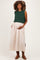woman wearing a dark green knitted crop top and a light beige maxi skirt, showcasing her baby bump in maternity wear