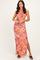 woman wearing a sleeveless floral maxi dress in pink and orange hues with a side slit