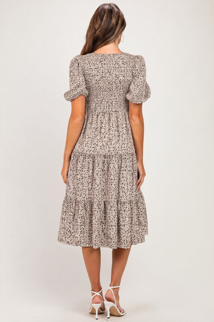 woman wearing a floral print maternity dress with puff sleeves and a tiered hem, showing her baby bump from the back