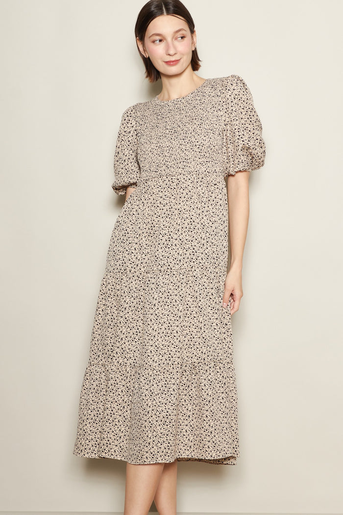 woman wearing a beige floral midi dress with puff sleeves and a tiered skirt