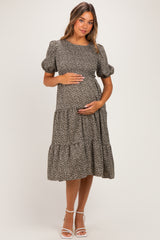 woman wearing a brown floral print maternity dress with short puff sleeves and a tiered skirt, showing her baby bump