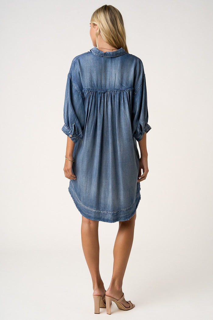 woman wearing a denim chambray shirt dress with three-quarter sleeves and a relaxed fit, shown from the back
