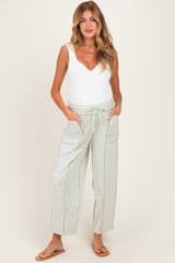 woman wearing a white maternity bodysuit and green gingham wide-leg maternity pants with pockets and a tie waist