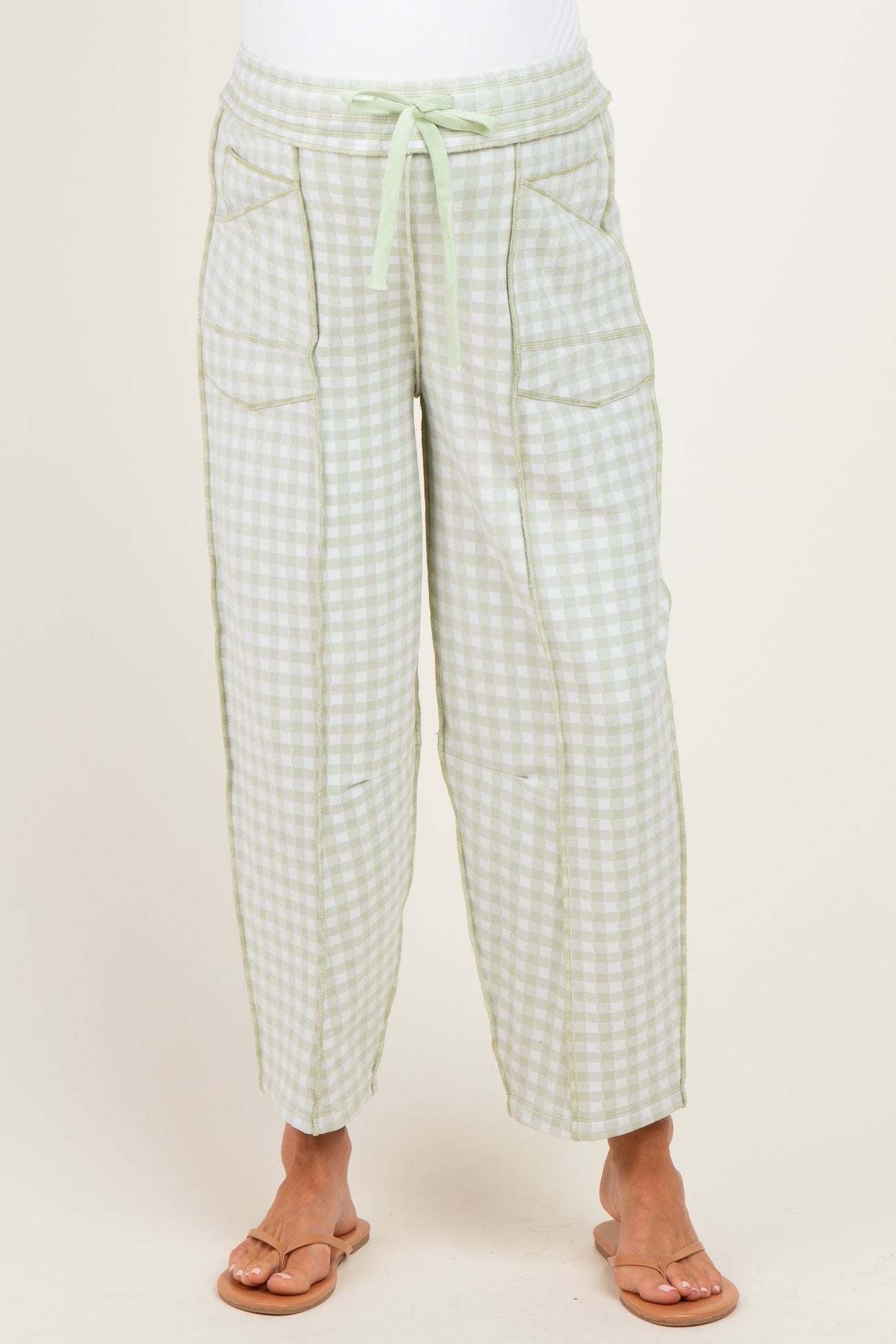 woman wearing green and white gingham maternity pants with pockets and a drawstring waist