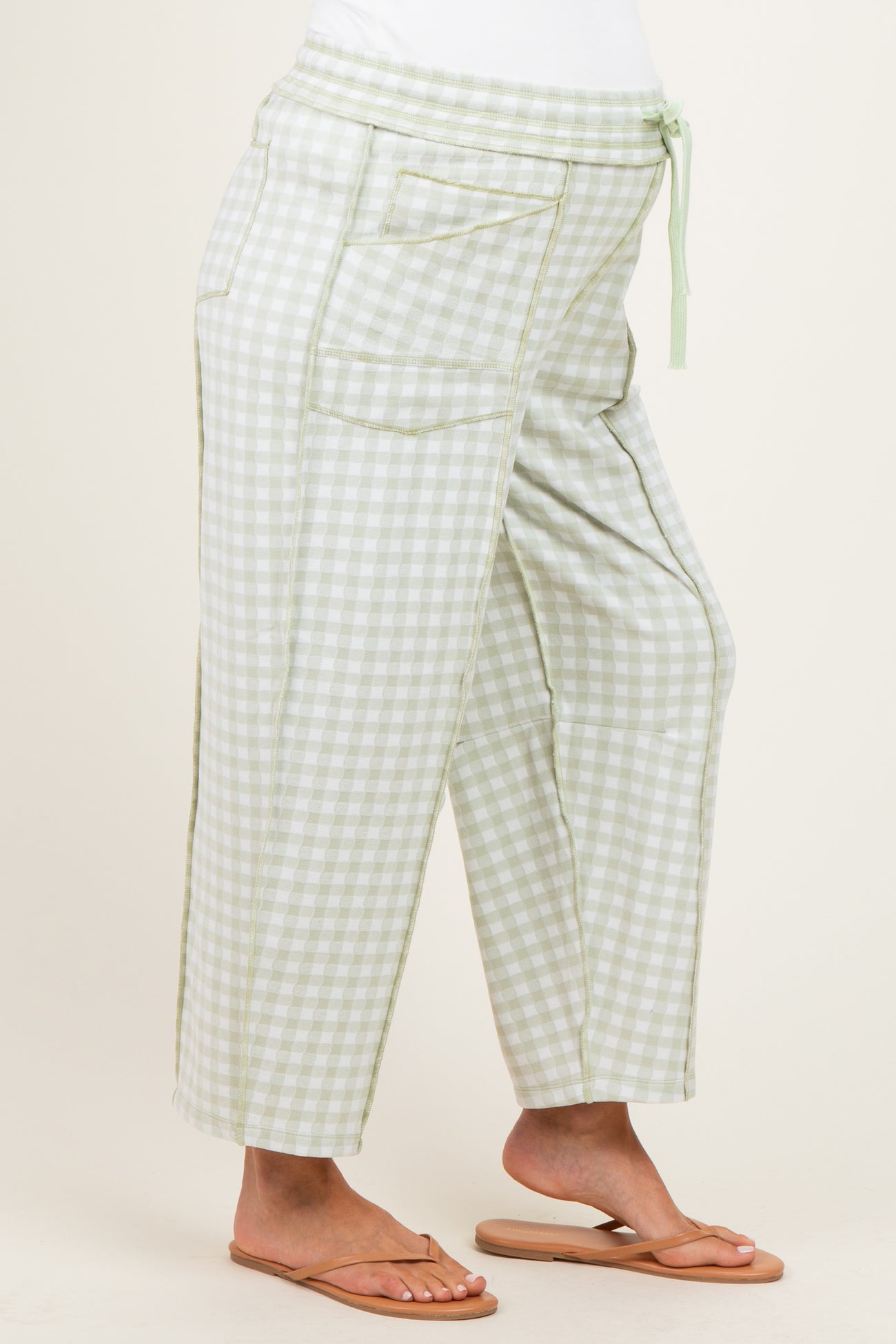 woman wearing maternity light green gingham check cropped pants with a drawstring waist and side pockets