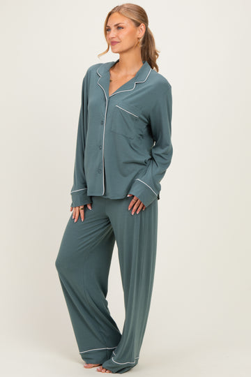 woman wearing a teal pajama set with a button-up top and wide-leg pants, featuring white piping details