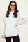 woman wearing an oversized cream turtleneck sweatshirt with long sleeves and a curved hem, paired with black pants