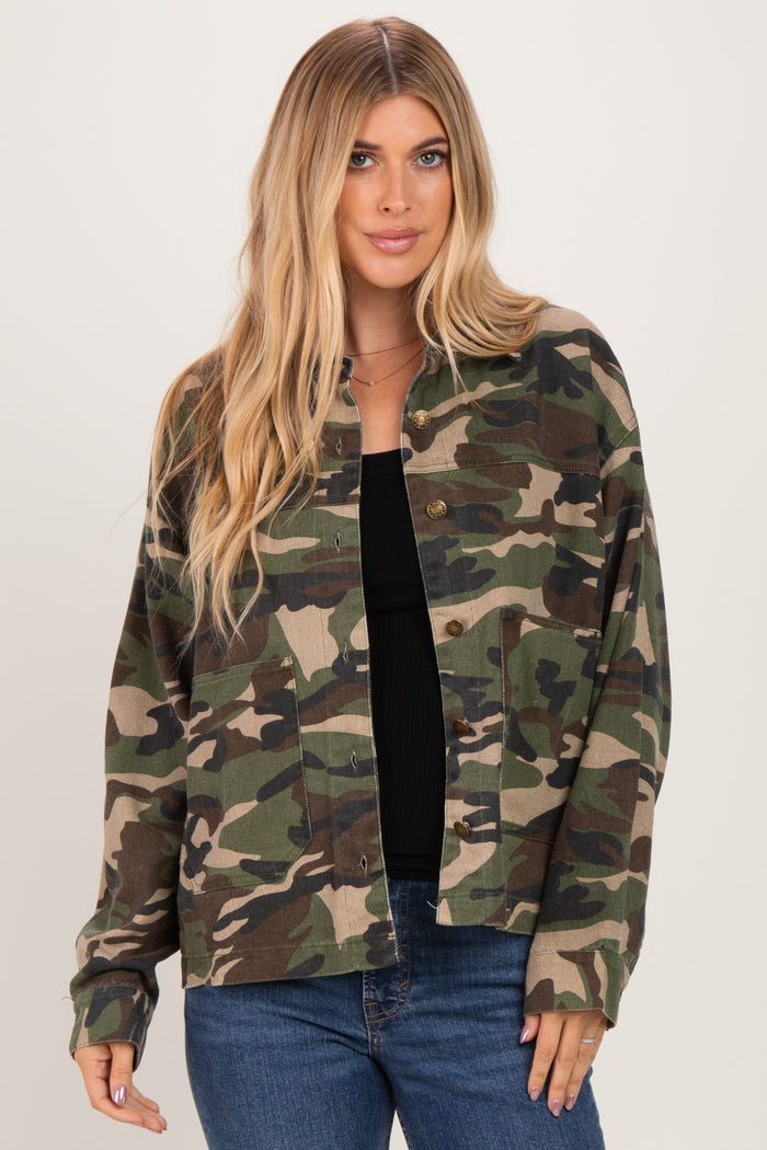woman wearing a green camouflage button-up jacket over a black top, styled with blue jeans