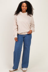 woman wearing a beige pullover sweatshirt with a ruffled collar and wide-leg blue jeans