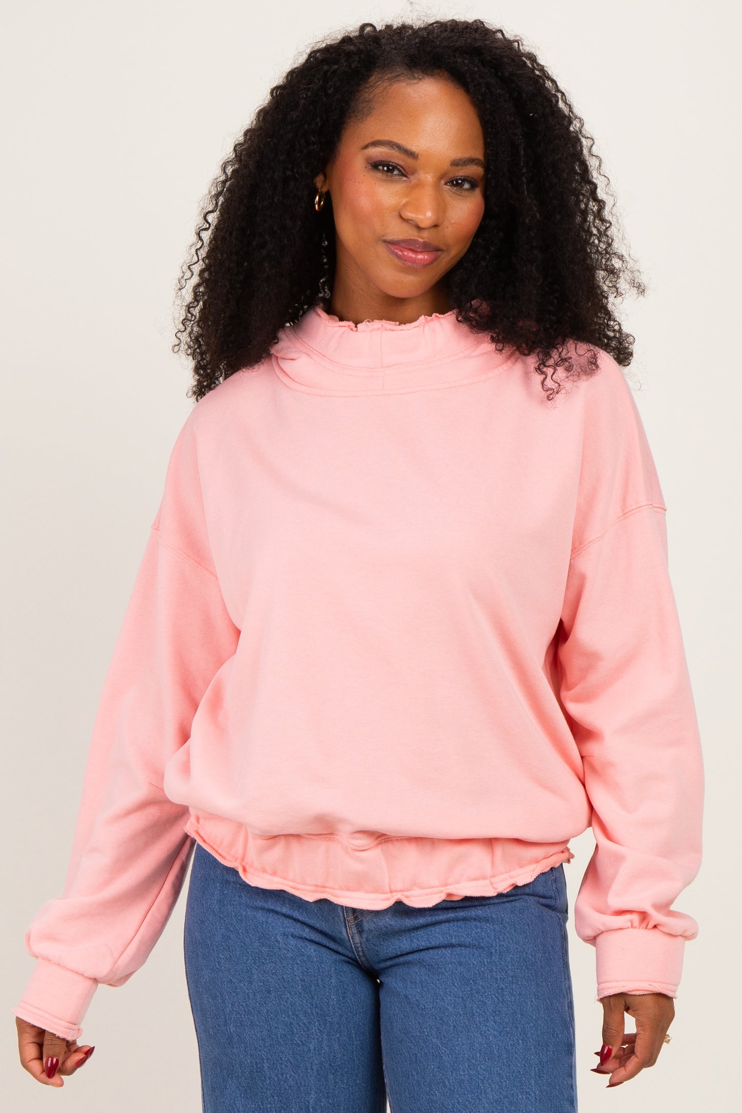 woman wearing a soft pink oversized sweatshirt with a ruffled collar and cuffed sleeves