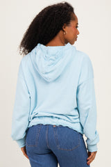 woman wearing a light blue hooded sweatshirt with a relaxed fit and ruffled hem, seen from the back
