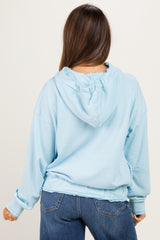 woman wearing a light blue oversized maternity hoodie, with a relaxed fit and adjustable hood, seen from the back