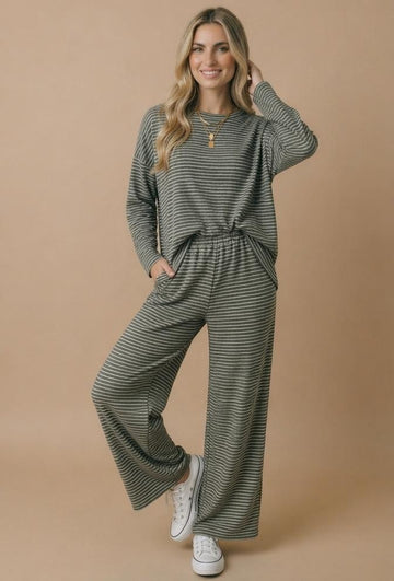 woman wearing a green and black striped long sleeve top and matching wide-leg pants with pockets and white sneakers