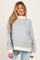 woman wearing a gray maternity sweatshirt with a floral pattern and cream-colored cuffs, styled casually