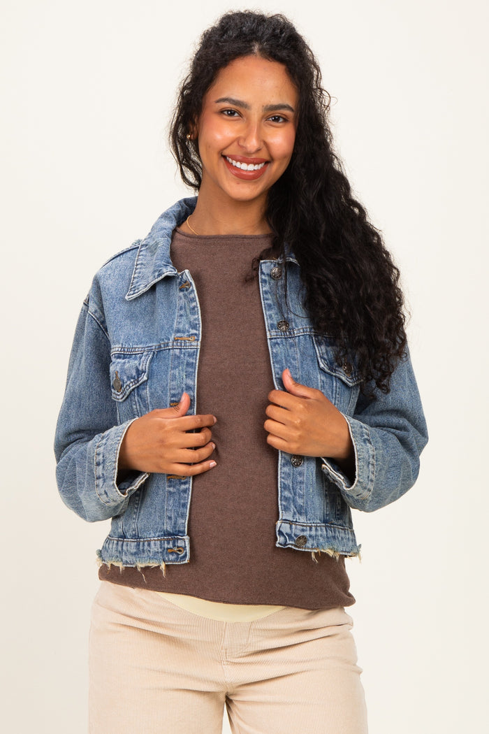woman wearing a light blue denim maternity jacket over a brown top, smiling at the camera