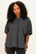 woman wearing a dark green and navy plaid oversized button-up shirt with rolled sleeves