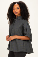 woman wearing a dark green checkered oversized button-up shirt with rolled sleeves and a relaxed fit