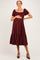 woman wearing a burgundy polka dot maternity dress with a square neckline and puff sleeves, holding her baby bump