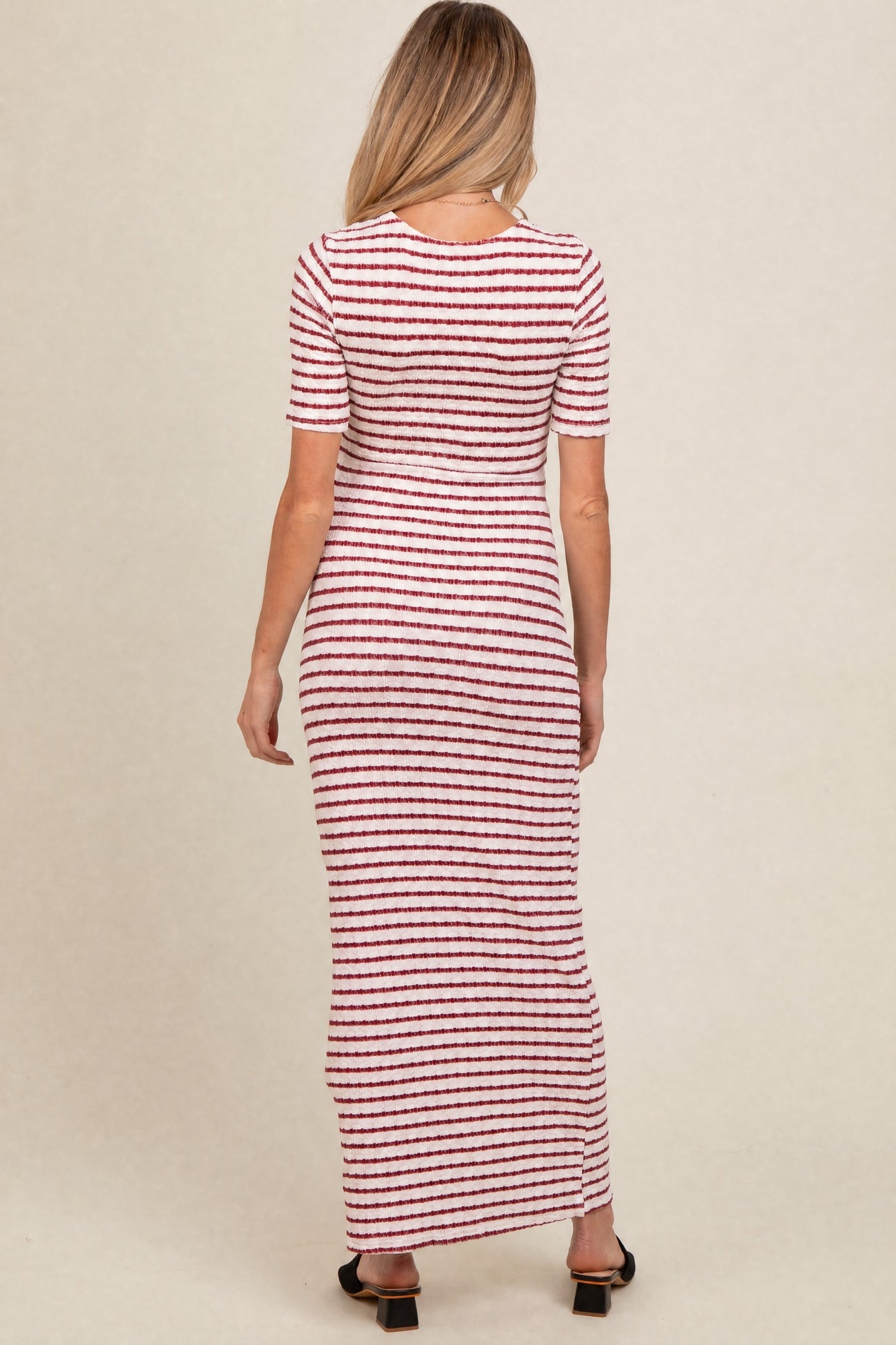 woman wearing a striped red and white long sleeve maternity dress, viewed from the back